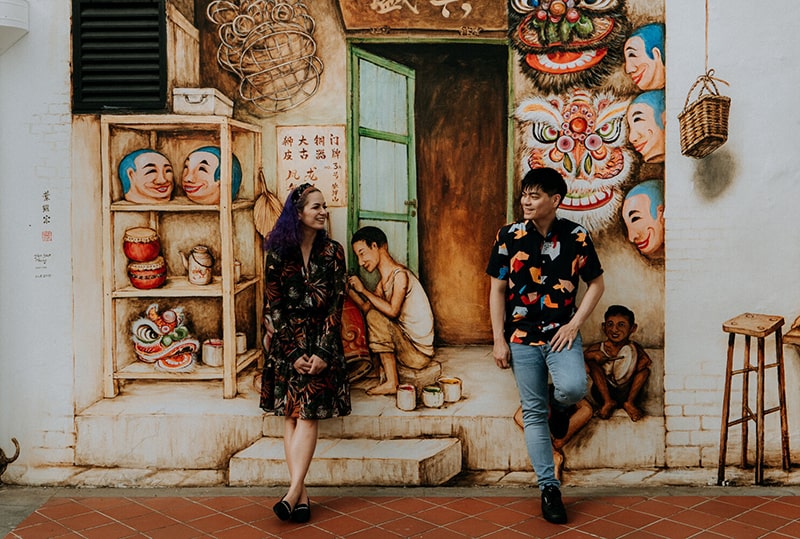 a photo of a couple posing in front of a mural