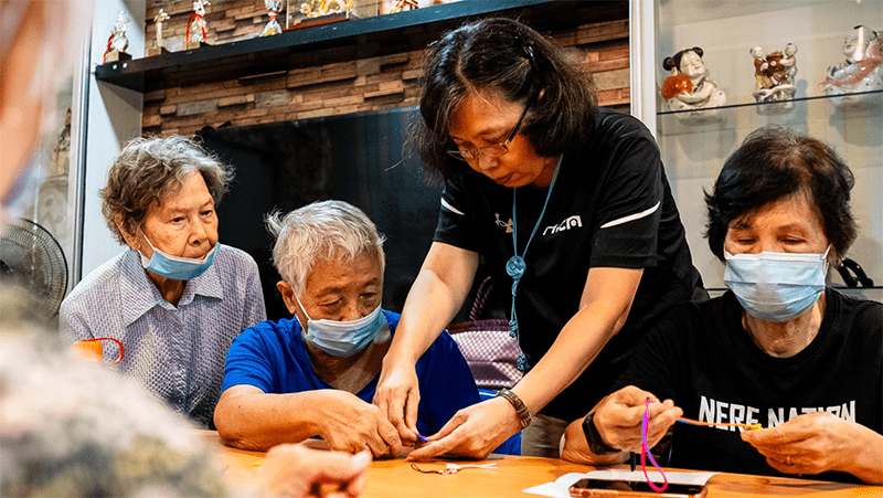 Ai Geok helping a senior tie a knot