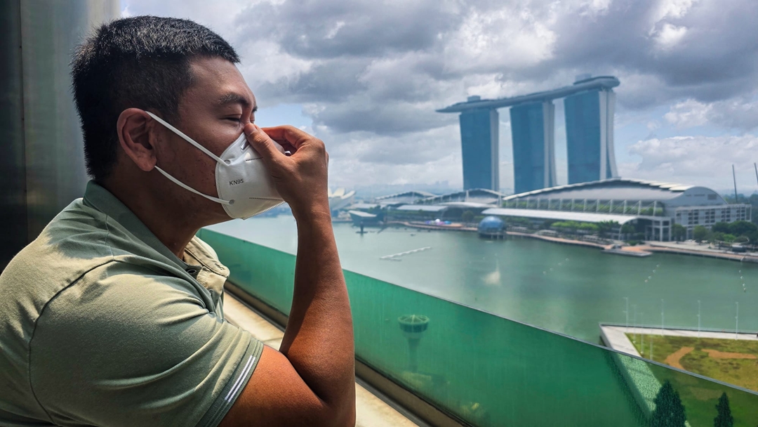 Worker checks the fit of an N95 mask before outdoor work.