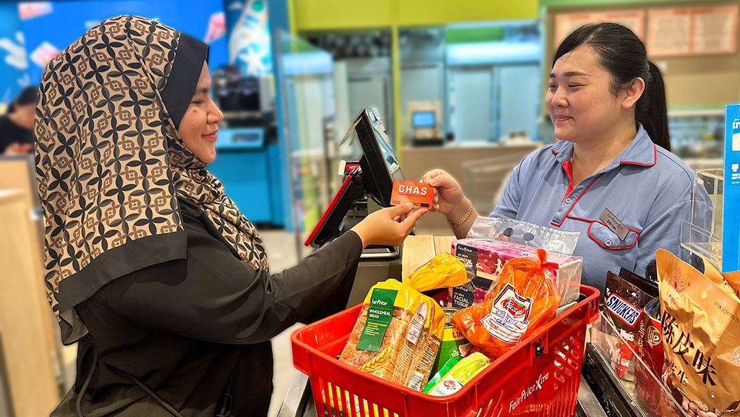 A shopper presenting her Orange CHAS card to get discounts at a FairPrice store.