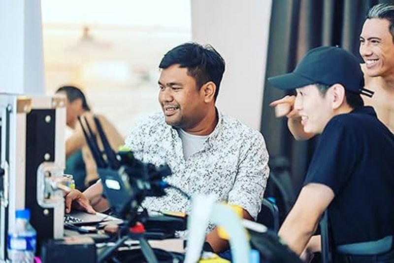 Yusri at a laptop showing his footage to his actors