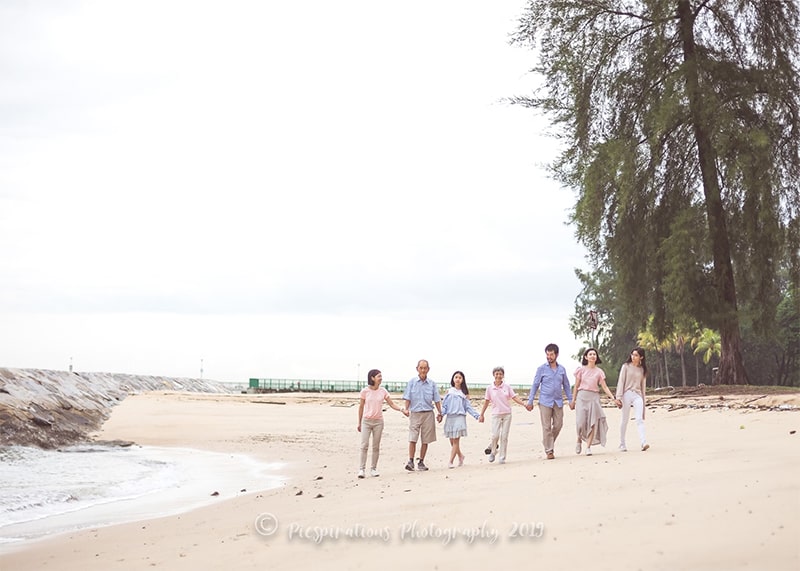 a multi-generational family walking beside the beach holding hands