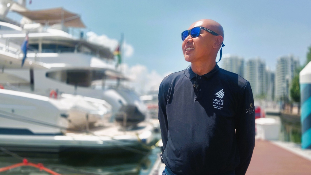 Man standing at a marina in Singapore, surrounded by boats.