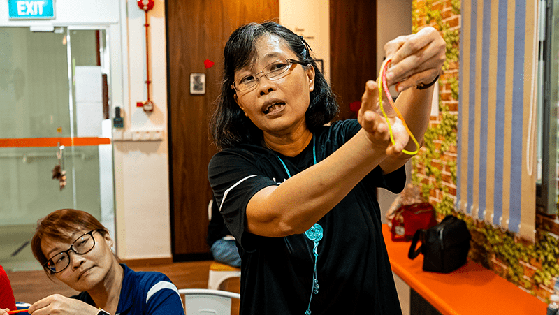 Ai Geok explaining how to tie a complex knot.
