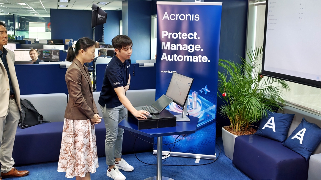 A worker from Acronis, a multinational cybersecurity and data protection software company, demonstrating a software to Acting Manpower Minister Jasmin Lau on 21 September 2026.